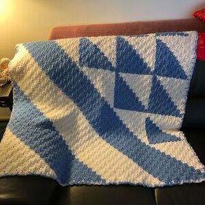 handcrafted crochet throw blanket featuring a blue and white geometric design